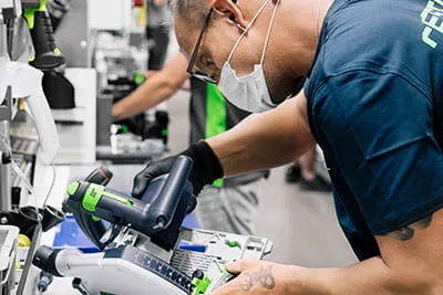 Elementy zagłębiarki TSC 55 K Festool są montowane na stole warsztatowym.