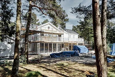 Widok na rusztowanie wokół drewnianego domu w szwedzkich lasach