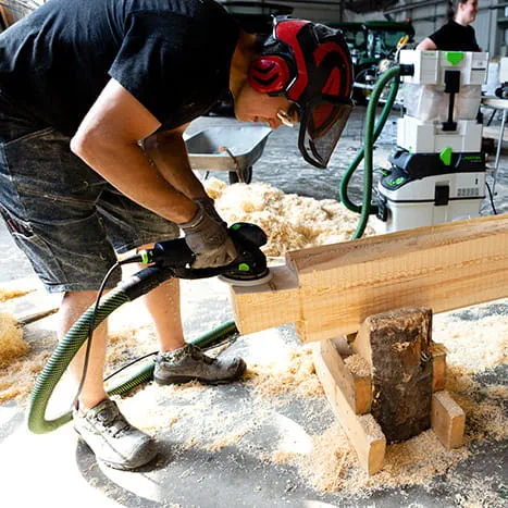 Konstruktorka sauny szlifuje drewnianą powierzchnię za pomocą narzędzia Rotex 150 firmy Festool.